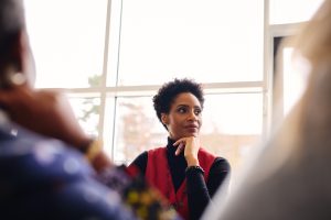 Woman looking to the side with hand under chin- thinking and holding insights to herself.