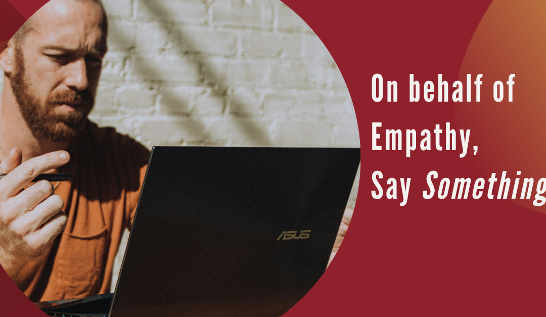 Man with beard and raised hand looking at a laptop. Text: On behalf of empathy, say something